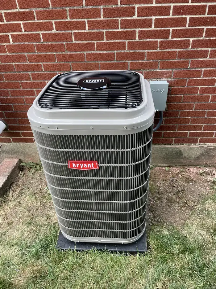 A newly installed Bryant air conditioning condenser on a pad beside a brick house