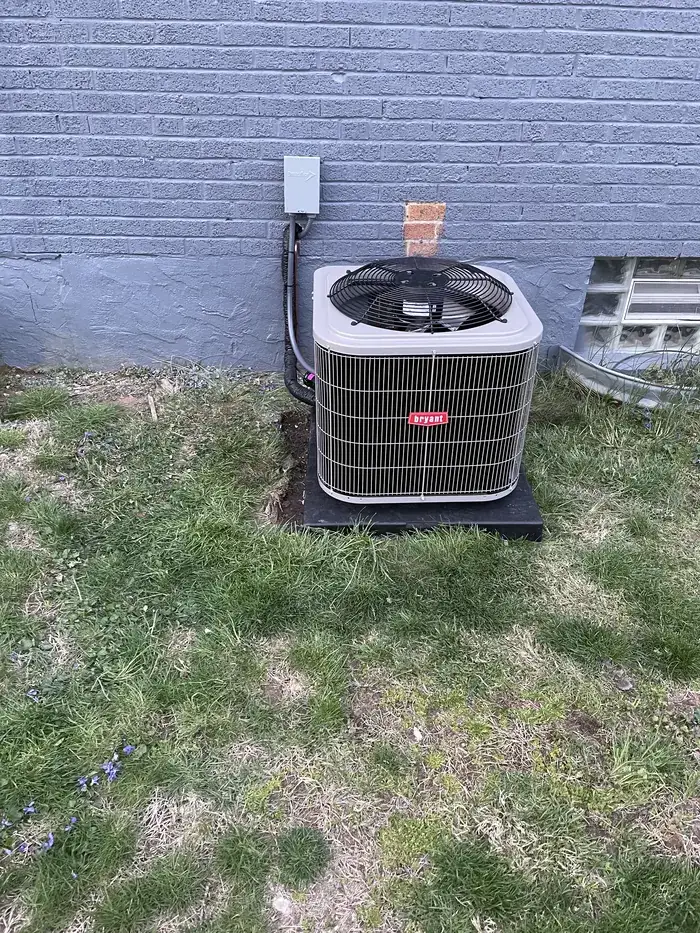 A Bryant condenser on a level pad beside a painted brick home