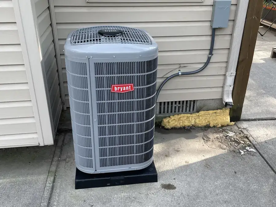 A newly installed Bryant air conditioning condenser on a level pad beside a home