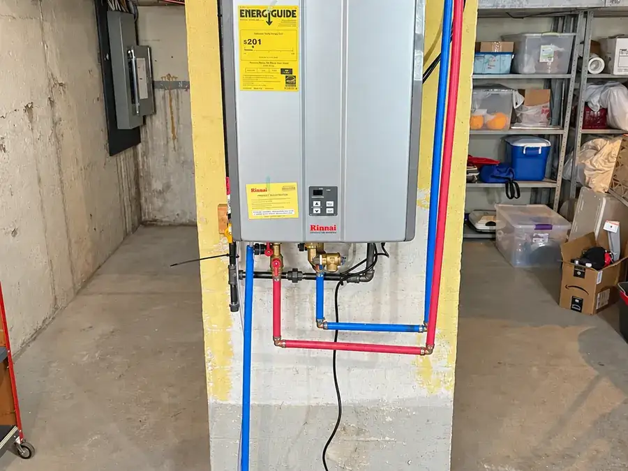 A wall-mounted tankless on-demand water heater with new supply lines in a basement