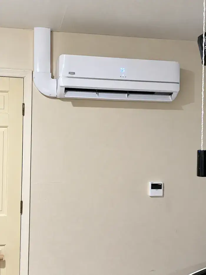 A wall-mounted ductless air handler with the line-set cover running up to the ceiling