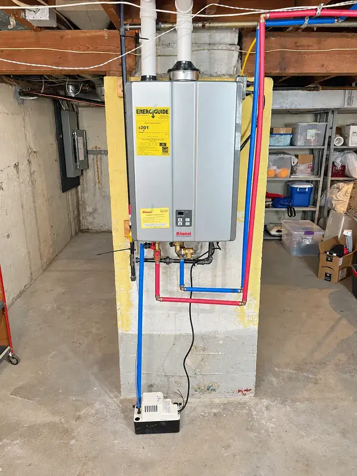A wall-mounted tankless on-demand water heater with new supply lines in a basement